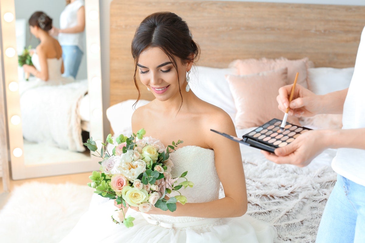 brunette bride in wedding dress looking down at bouquet