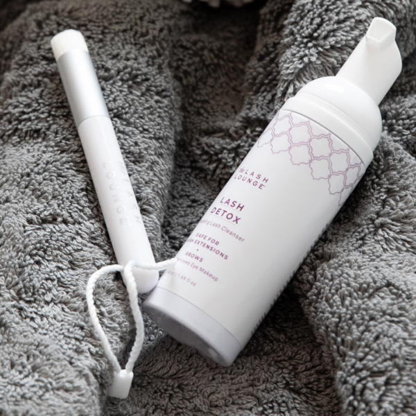 Lash Detox foaming cleanser and brush resting on a bath towel