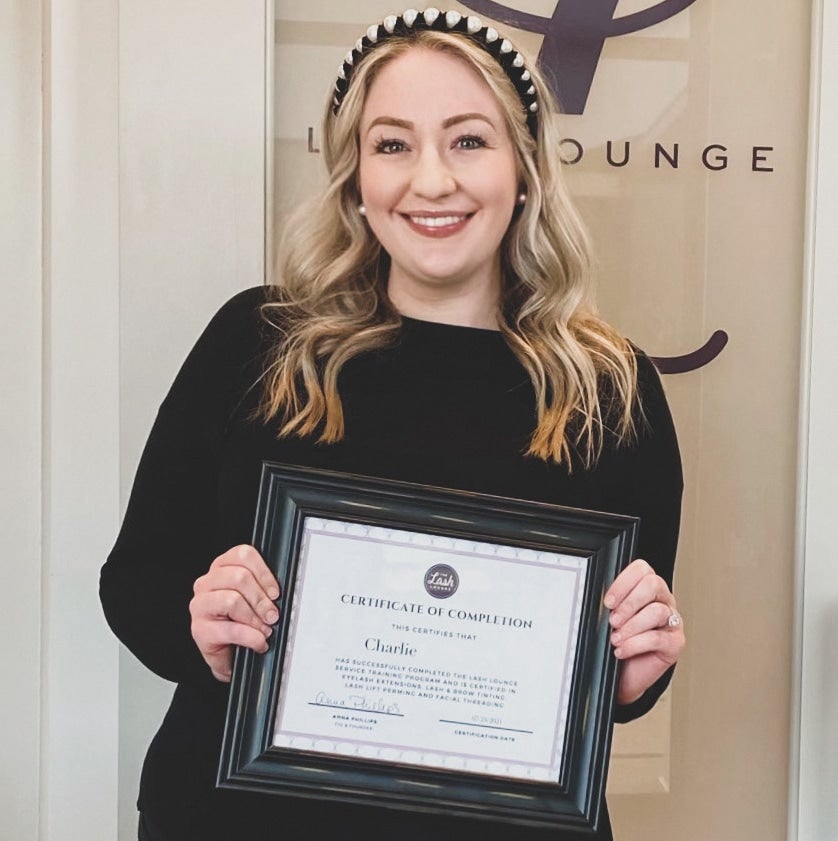 The Lash Lounge stylist holding up certificate for eyelash extension jobs