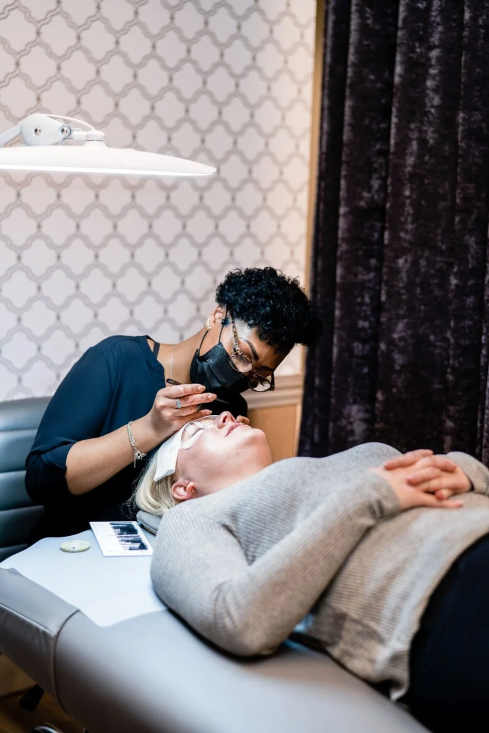 Lash stylist applying eyelash extensions to guest