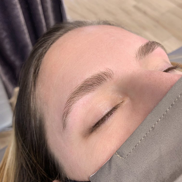 close-up of woman's face with her eyes closed while focussing on her freshly threaded eyebrows
