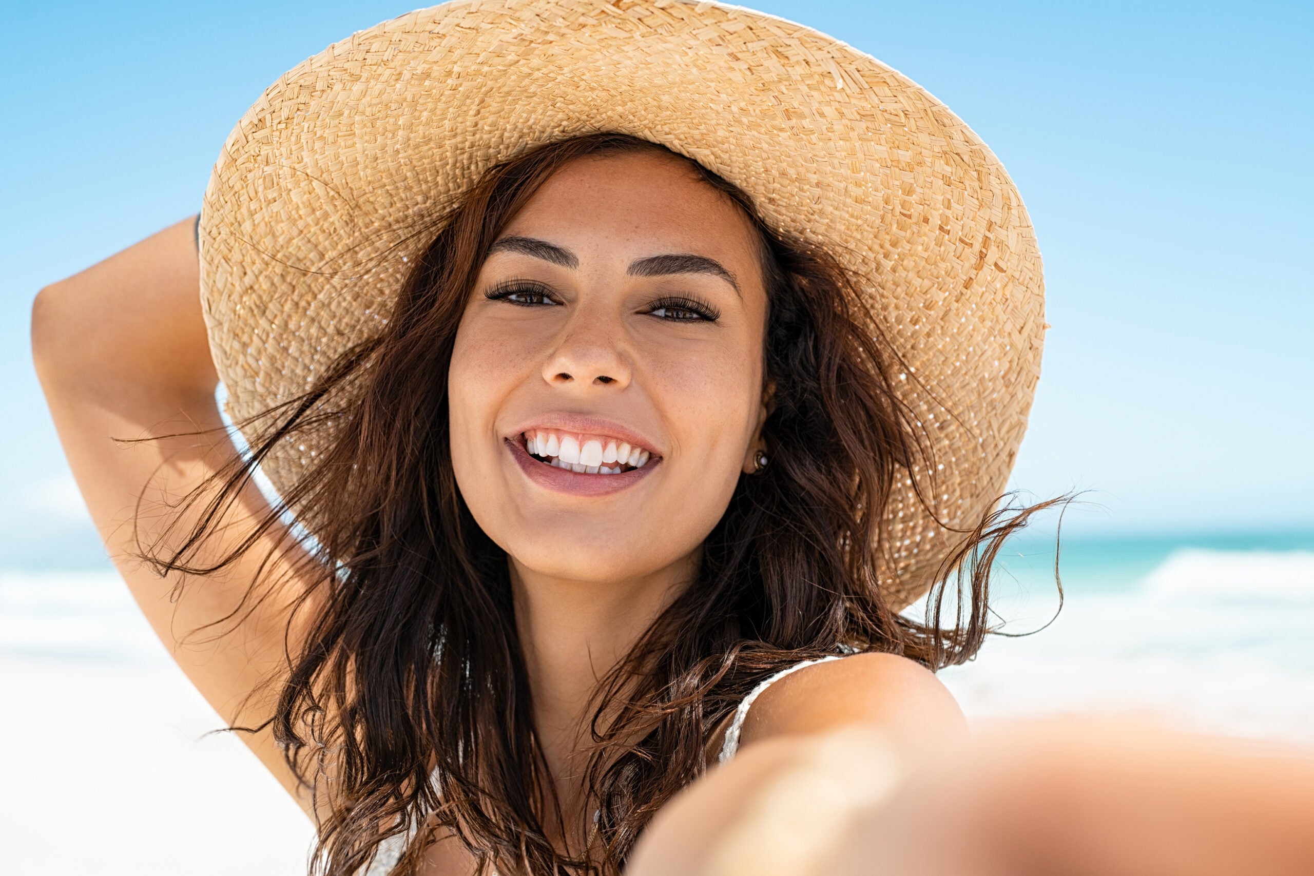 mid-shot of woman in hat on beach with natural lash lift