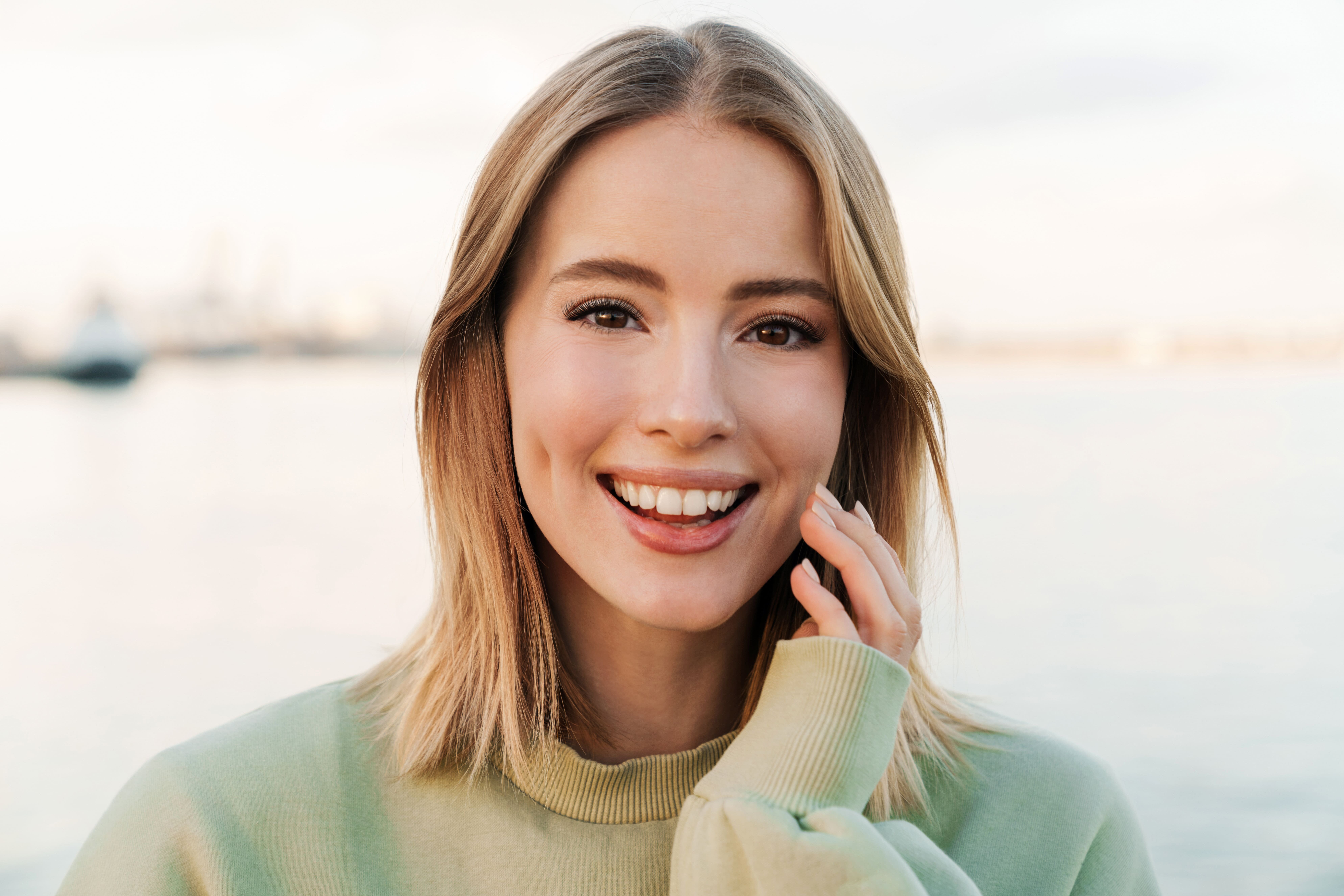 Young blonde woman on beach smiling with lash lift