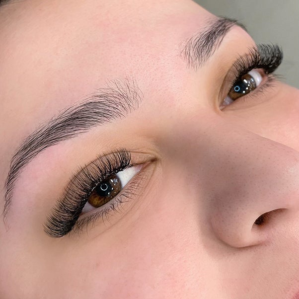 A close-up of brunette woman's natural looking lashes and brows