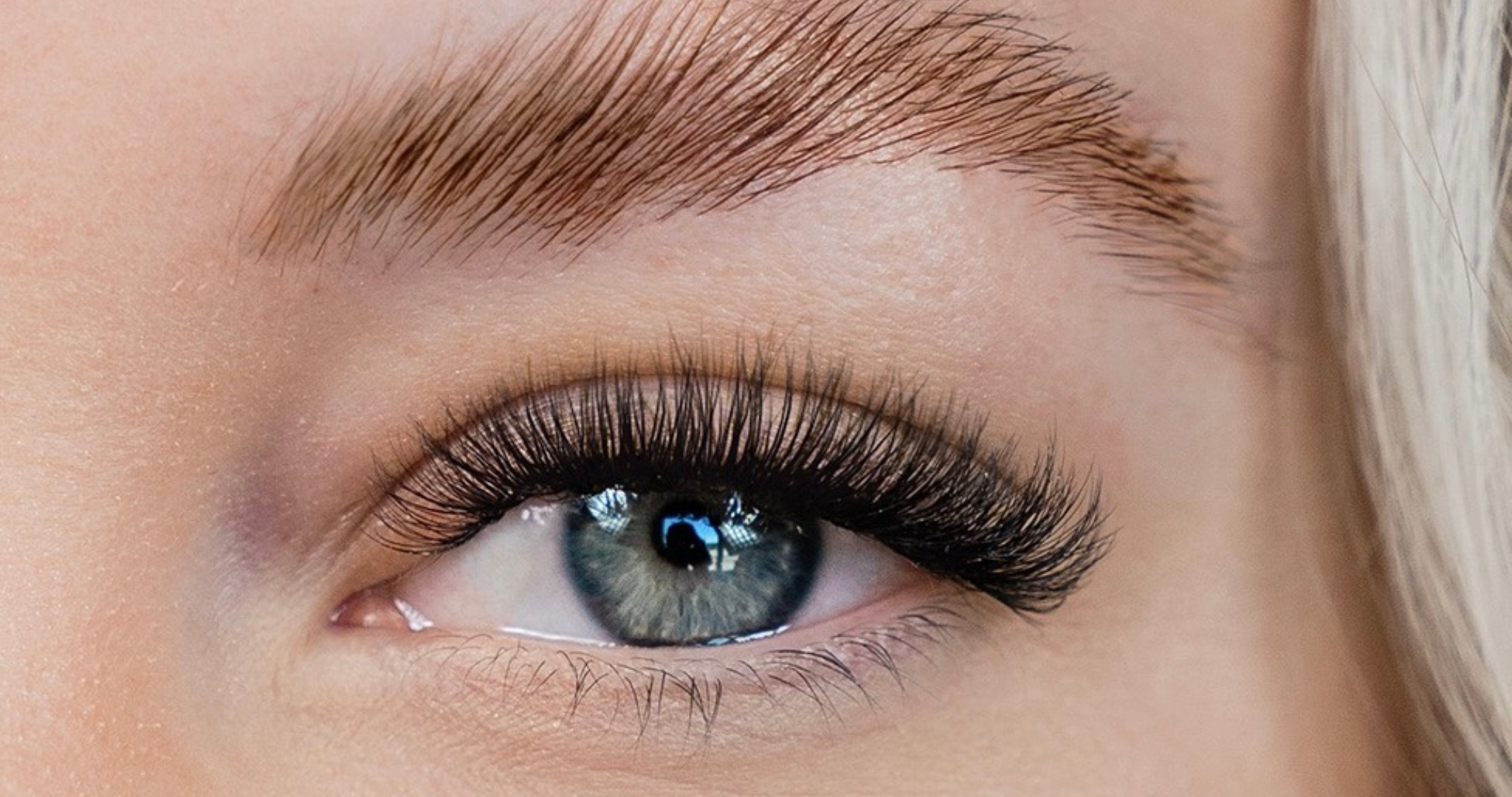A close-up of a woman's eye with lash extensions and brow lamination