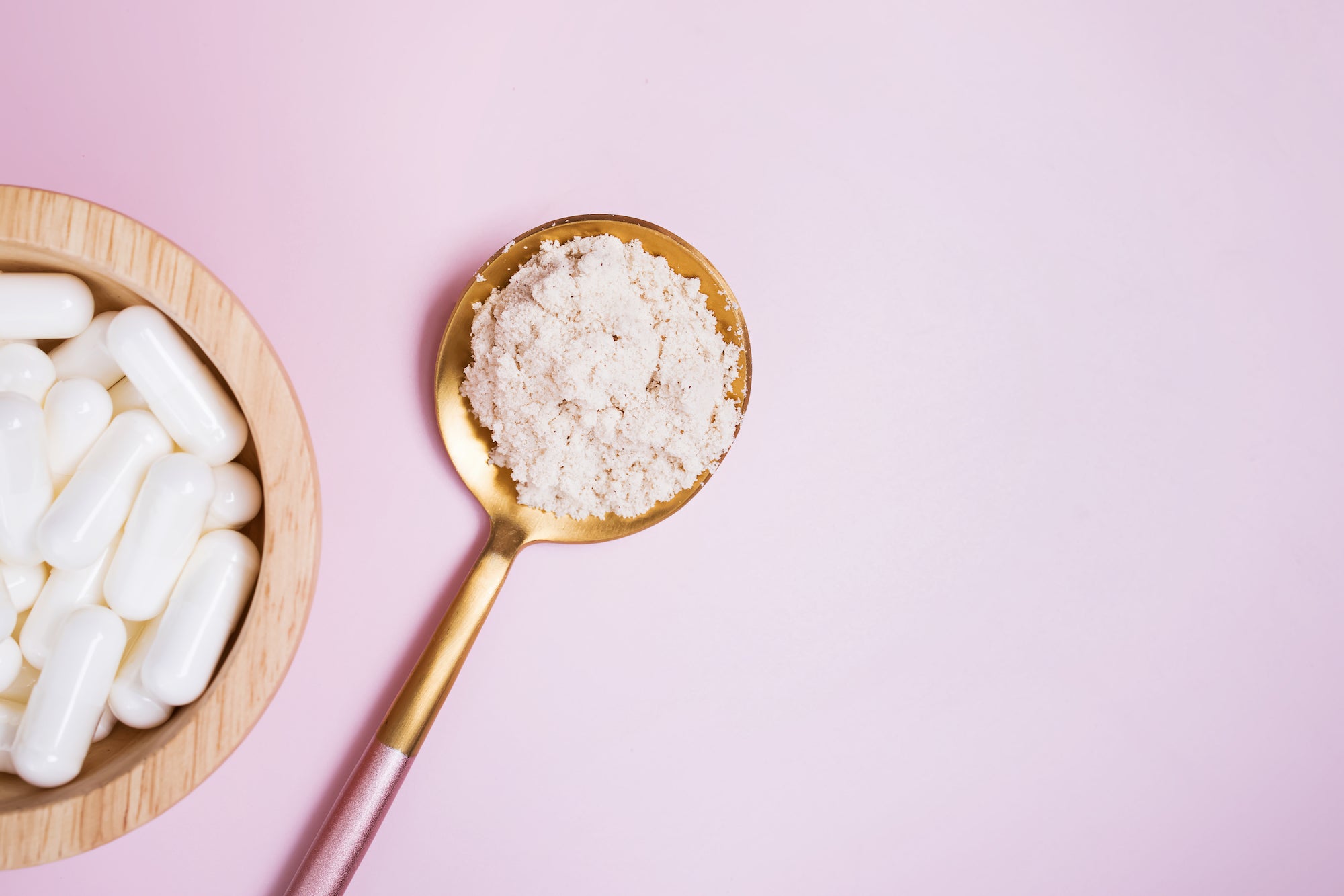 gold spoon with collagen powder and small bowl with biotin supplements