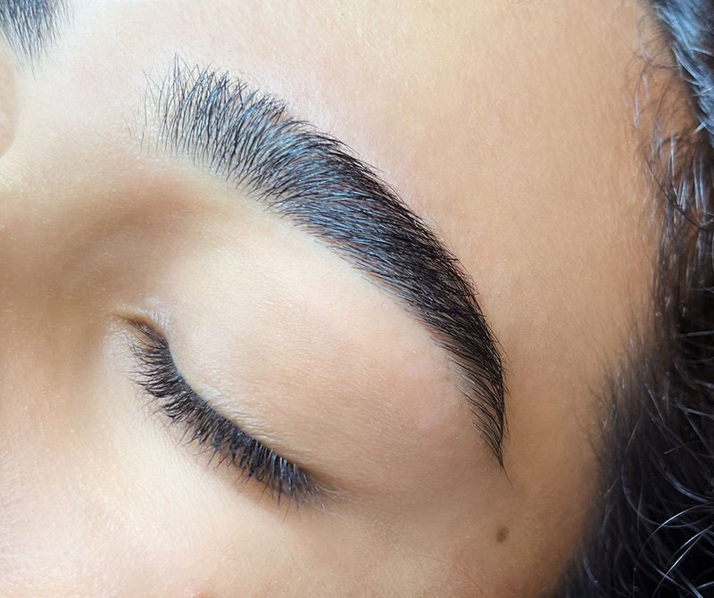 close-up of white woman's closed eyes with threaded brows