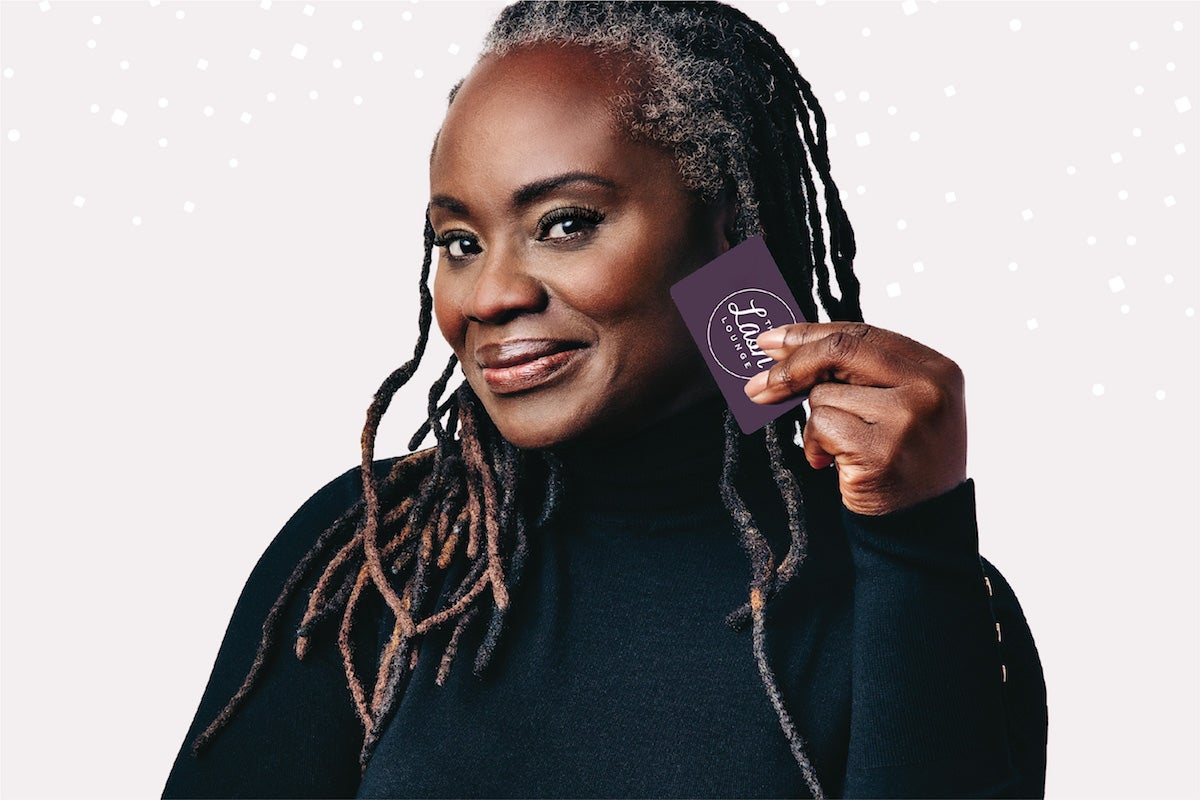 mature black woman smiling and holding Lash Lounge Gift Card