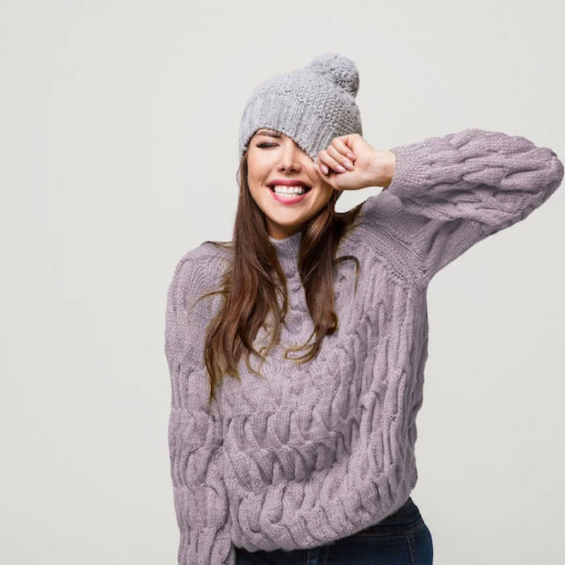 A woman standing indoors in a lavender sweater