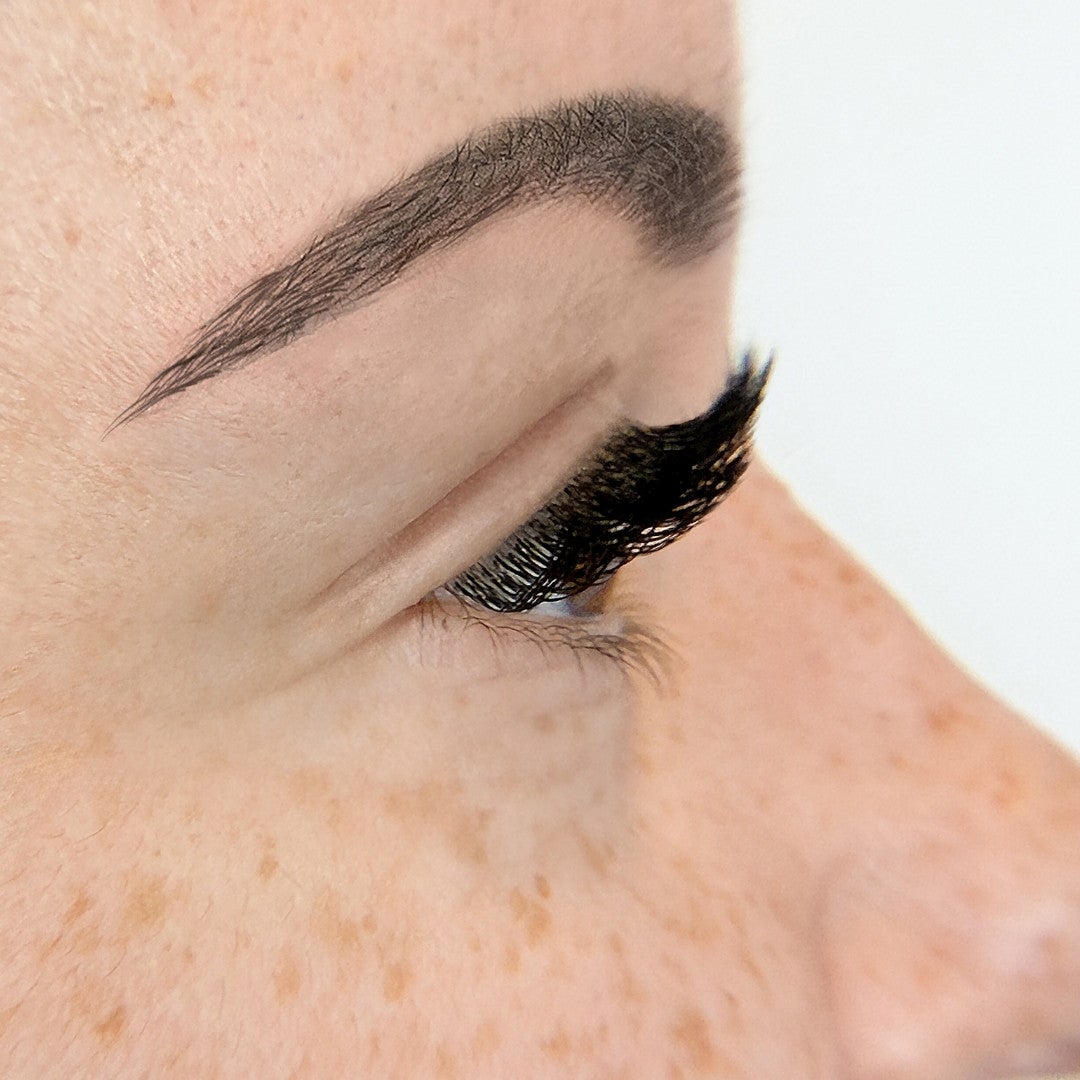Side profile of CC curl lash extensions applied on a woman with monolid eyelids.