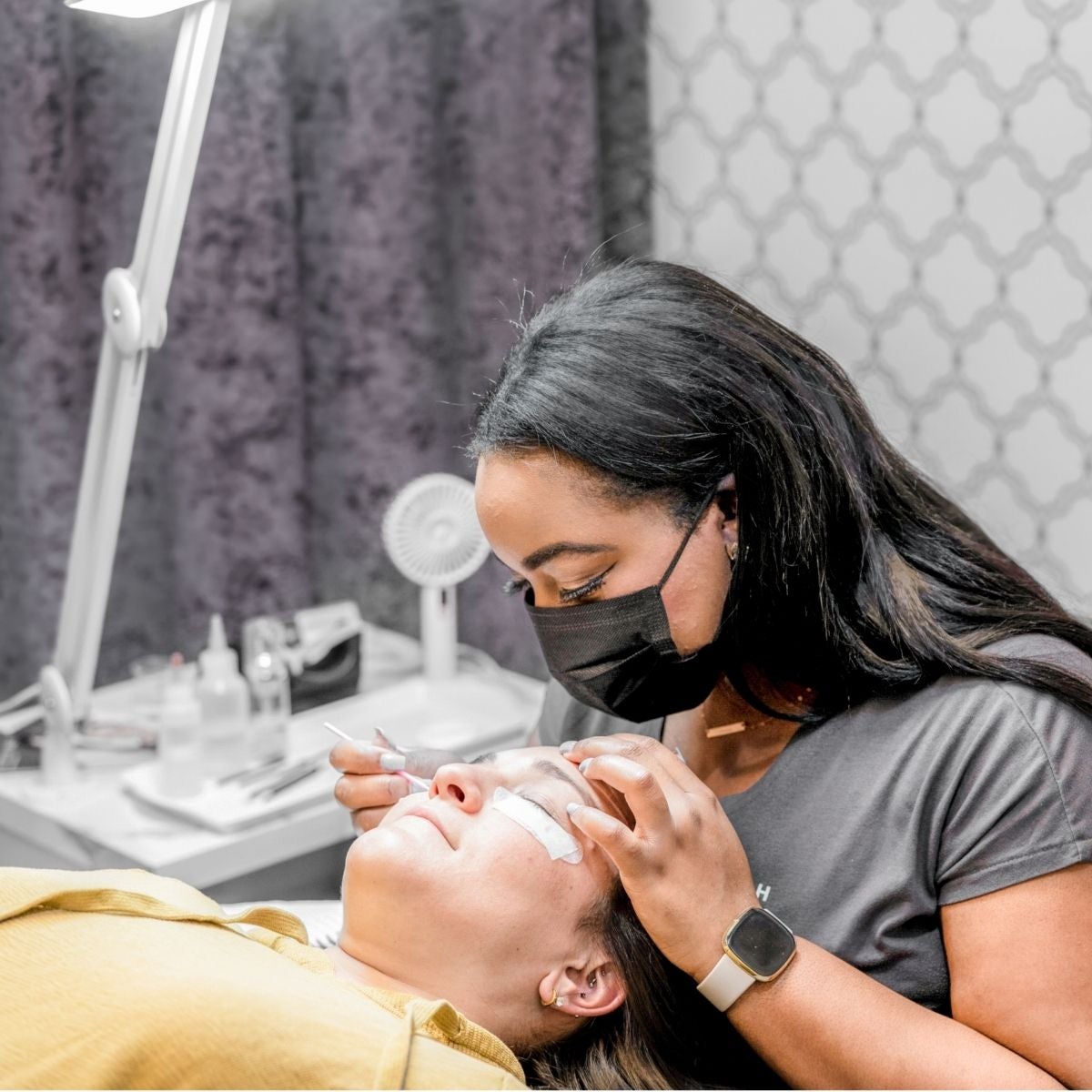 Stylist at The Lash Lounge providing a lash lift treatment to guest laying back in chair.