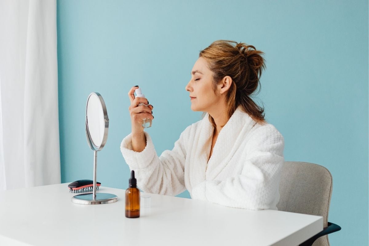Woman spraying hypochlorous acid on her face as part of a skincare routine