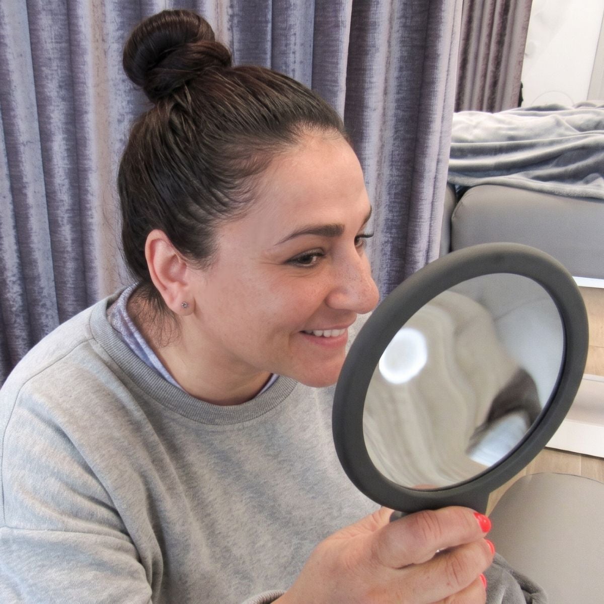 Guest at The Lash Lounge looking in the mirror at new set of lash extensions.